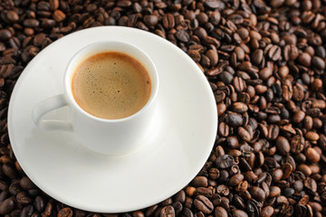 cup of coffee espresso and plate on coffee beans background