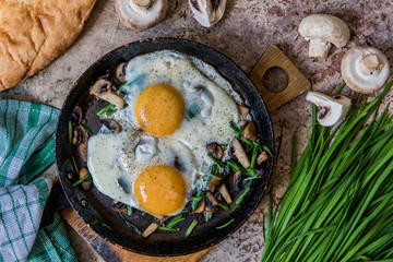 Fried eggs with mushrooms and jusai (allium ramosum). Breakfast in azian style, top view