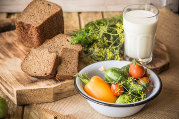 Bread, milk and vegetables on a wooden background in rustic style