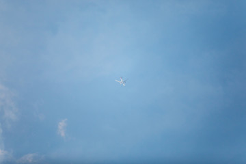 Small unspecified white plane in the center photo with blue sky and behind little clouds.