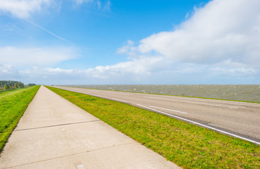 Road on a dike along a stormy lake in autumn
