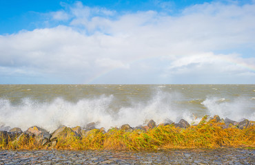 Dike along a stormy lake in sunlight in autumn