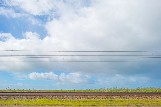 Railroad below a blue cloudy sky in autumn
