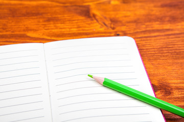 Notepad with pencil on wood board background