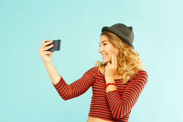 Portrait of a beautiful young woman making selfie on smart phone. Happy young woman photographing herself.