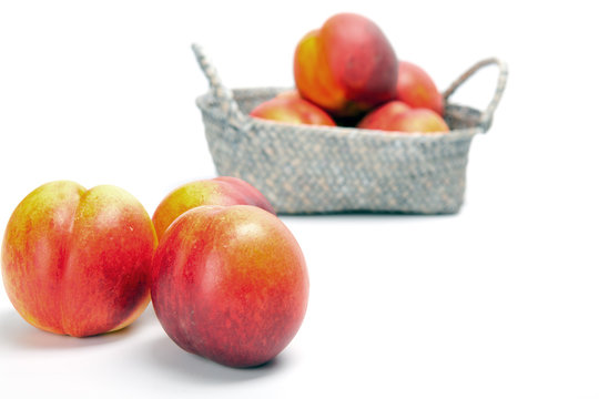 Ripe fresh nectarines in the wicker basket isolated on a white background
