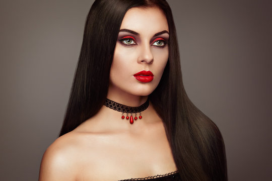 Halloween Vampire Woman portrait. Beautiful Glamour Fashion Sexy Vampire Lady with long dark Hair, beauty Make Up and Costume