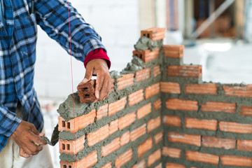 Construction worker build home by use cement mortar  to lay brick wall with a trowel follow vertical and horizontal guid line