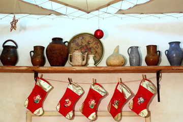 Hholiday decorated home room with red Christmas socks and with clay jugs on the shelves