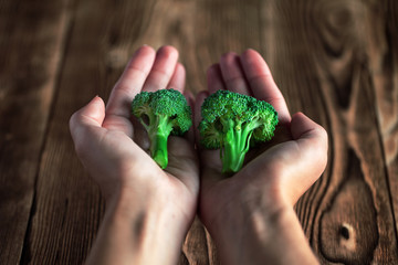 broccoli in hands on a background a wooden table