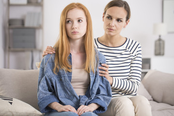 Worried mother supporting young daughter