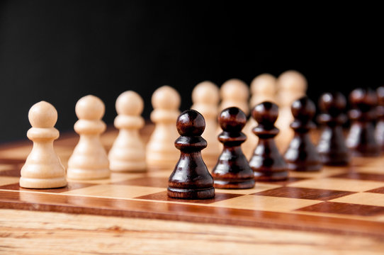 Still life on the chessboard: white and black pawns stand in a row