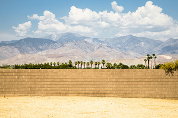 Looking beyond a brick wall in Palm Springs with the famous wind turbines in the background - obrazy, fototapety, plakaty