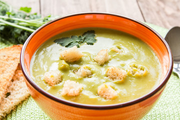 Pea soup in an orange plate with crackers