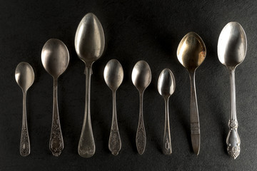 Different spoons on a black stone top view
