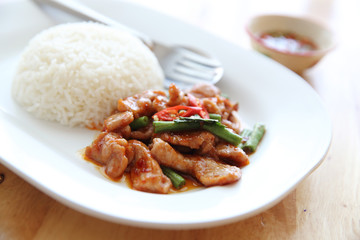 fried pork with thai curry and rice on wood background , Thai food