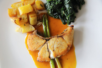 Sea bass fillet steak with potatoes and spinach in lemon sauce