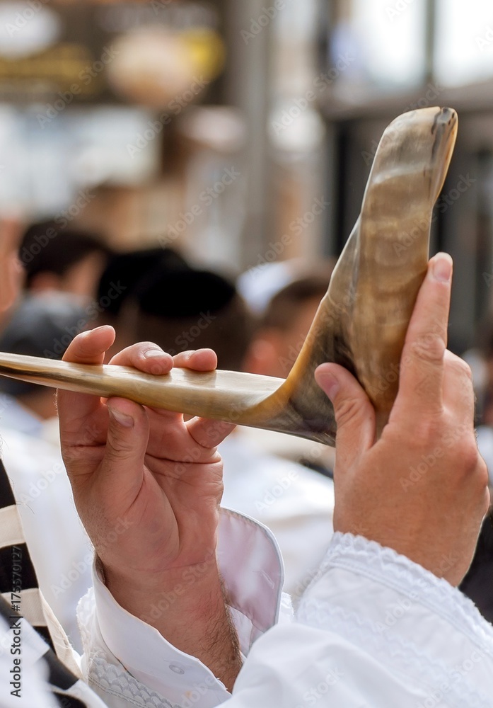 Wall mural jewish hasid blows shofar. hands and shofar close-up.