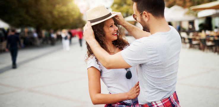 Charming young man putting a hat on a girlfriend in the romantic walk.