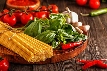 Products for cooking - pasta, tomatoes, garlic, pepper, and basil.