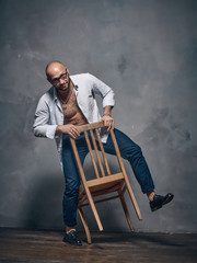 A man in a white shirt is dancing with an old wooden chair.