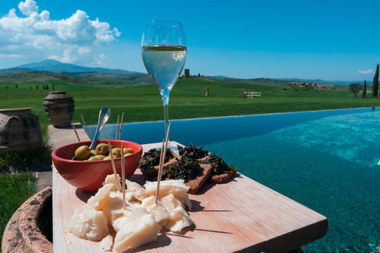 Spring aperitif in Tuscany / Closeup view of a traditional apetizer serving dish on a magnificent swimming pool in the Tuscan countryside