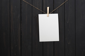 Blank white paper card hanging on clothespins