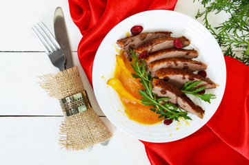 Goose breast Magret in berry sauce with caramelized pear, arugula on a white plate. Provencal festive dish. French cuisine.