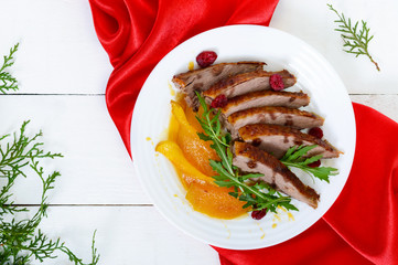 Goose breast Magret in berry sauce with caramelized pear, arugula on a white plate. Provencal festive dish. French cuisine.
