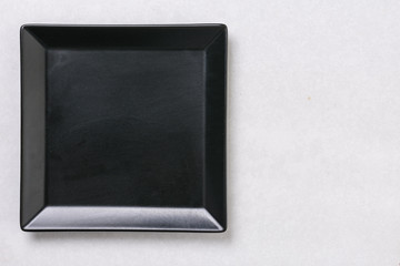 Flat lay above black square plate on the white marble table background