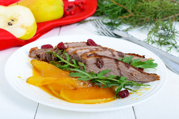 Goose breast Magret in berry sauce with caramelized pear, arugula on a white plate. Provencal festive dish. French cuisine.