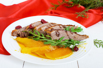 Goose breast Magret in berry sauce with caramelized pear, arugula on a white plate. Provencal festive dish. French cuisine.