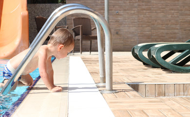 The cute baby getting out from the swimming pool