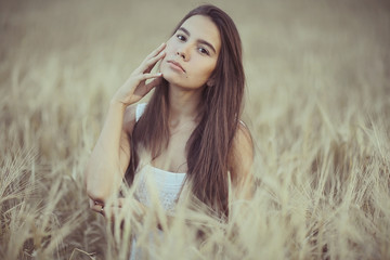 Naklejka premium Dreaming in a wheaten field beautiful young adult woman