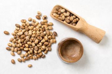 Flat lay above soya beans with wooden spoon above white marble background