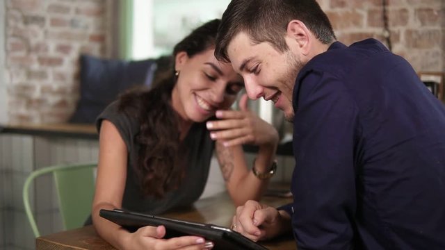 Romantic young couple using tablet in coffee shop. Woman's hands pointing at the touchscreen