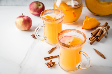 Halloween, Thanksgiving. Traditional autumn, winter drinks and cocktails. Spicy hot pumpkin sangria, with apple, cinnamon, anise. On a white marble table, in glass mugs. Selective focus, copy space