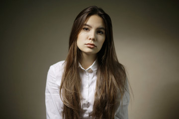 Fototapeta premium Portrait of a young adult woman in a white shirt thoughtful