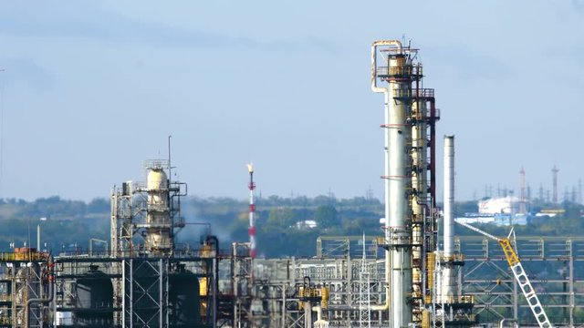 Long shot of oil refinery units in sunny weather with clouds in background. Gas industry background.