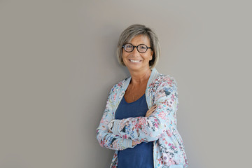 Obraz premium Portrait of mature woman with eyeglasses on grey background