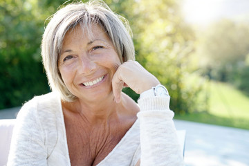 Portrait of cheerful senior woman relaxing in outdoors sofa