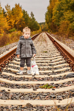 sad little boy alone on rails in the forest with toy bunny 