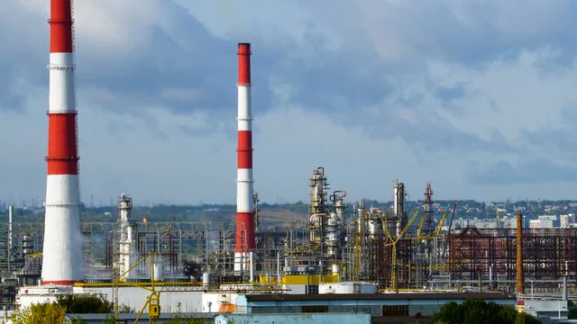 Long shot of oil refinery units in sunny weather with clouds in background. Gas industry background.