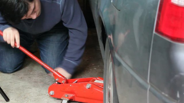 young man lifts car with jack