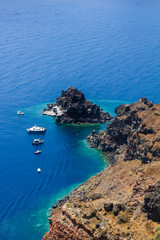 Fototapeta premium Boats in the sea near the coast of Oia village on Santorini island, Greece