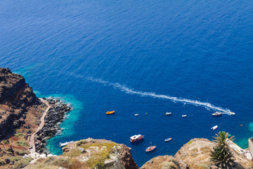 Boats in the sea near the coast of Oia village on Santorini island, Greece