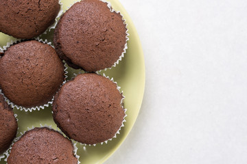 Flat lay above chocolate cup cakes on the white marble background with copy space