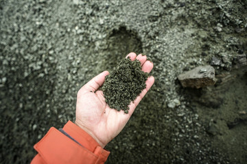 Female hand holding clump, volcanic dust in the mountains of Iceland.