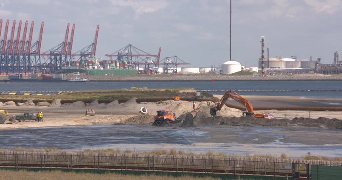 dredging pipes and slurry, the creation of Europe s first offshore centre at Maasvlakte 2 OCMV2.  Euromax container terminal in background. ROTTERDAM SEAPORT- AUGUST 2017