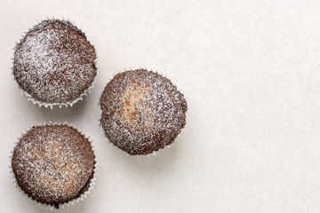 Flat lay above chocolate brownies cup cakes with powdered sugar on the white marble background